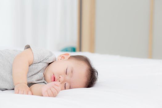Portrait of asian little baby girl sleeping on bed in the bedroom at home, newborn napping with cozy and relax, infant innocence in bedtime, happy toddler cute, growth of child and emotion, indoors.