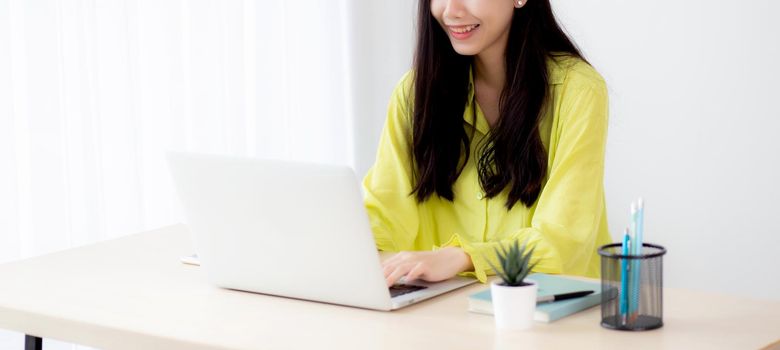 Young asian businesswoman working on laptop computer on desk at home office, freelance looking and typing on notebook on table, lifestyle of woman studying online, business and education concept.
