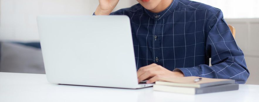 Young business man in glasses working from home with laptop computer on desk, freelance male sitting stay home using notebook for communication on table, entrepreneur in startup business, new normal.