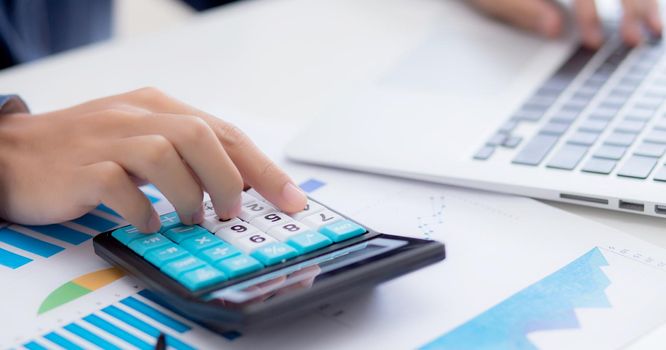 Hand of young asian business man working using calculator for planning accountant, graph for finance and report statistics, investment and profit of income, businessman analyzing with chart.