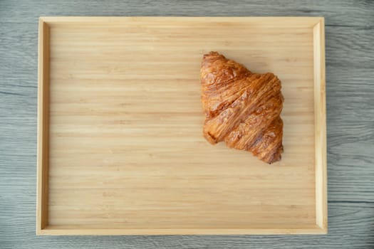 Serving baked crispy croissants on wooden tray.