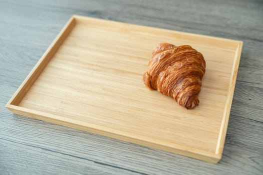 Serving baked crispy croissants on wooden tray.