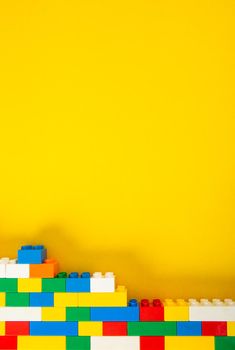 Plastic building blocks on yellow background