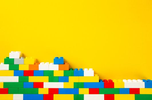 Plastic building blocks on yellow background