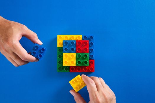 hand stacking up the colorful plastic block