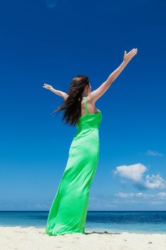 Happy woman enjoy summer vacation on beach standing with raised hands