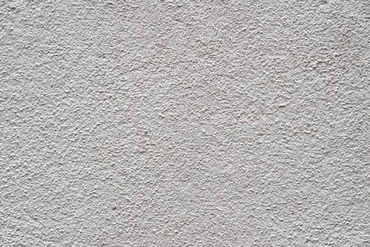 The heavy surface texture of an external wall covered in white plaster.