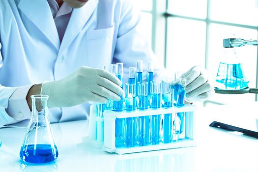 An Asian scientist or chemist drops a blue liquid chemical in a laboratory. Research concepts in healthcare, pharmacy, and medicine. Liquid analysis to separate DNA and molecules in vitro.