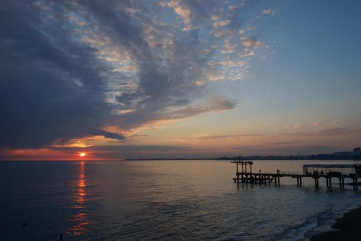 dramatic sunset with dark clouds over the calm sea.