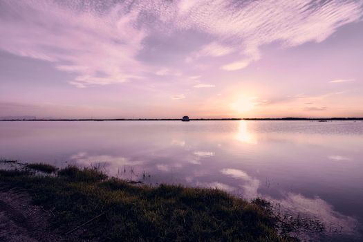Sunset on the lake, with clouds. Rustic house, vegetation, sun. long exposure, Albufera Valencia