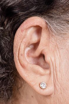 closeup senior woman's ear with earring, healthcare and medical concept