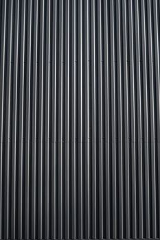 Black corrugated iron sheet used as a facade of a warehouse or factory. Texture of a seamless corrugated zinc sheet metal aluminum facade. Architecture. Metal texture