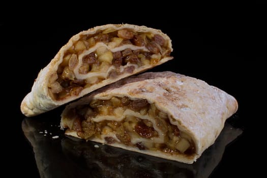 Apple strudel cut close-up on a black background;