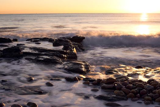 Sunrise on the rocky beach, long exposure, water silk effect