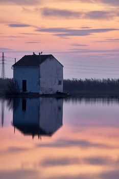 House reflected on the water of the lake, boat and birds, sunset,