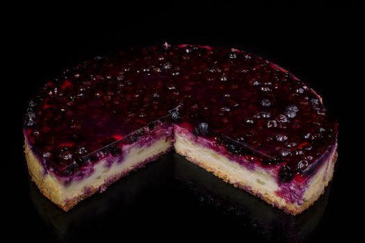 Piece of cake cheesecake with currant in jelly on black background