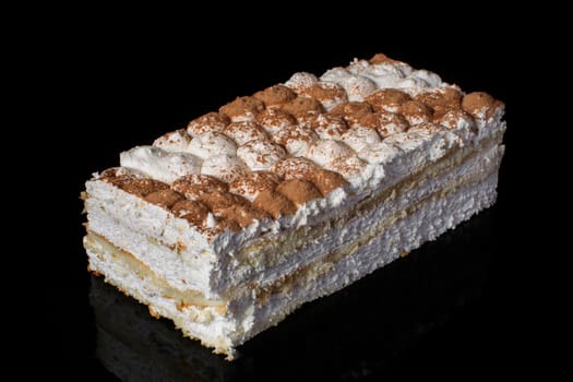 A piece of cake closeup with white cream sprinkled with cocoa