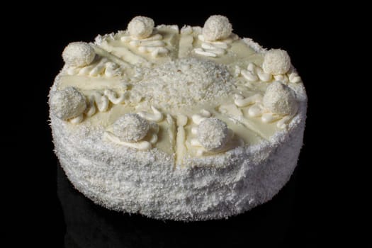 White cake closeup with coconut shaving on a black background