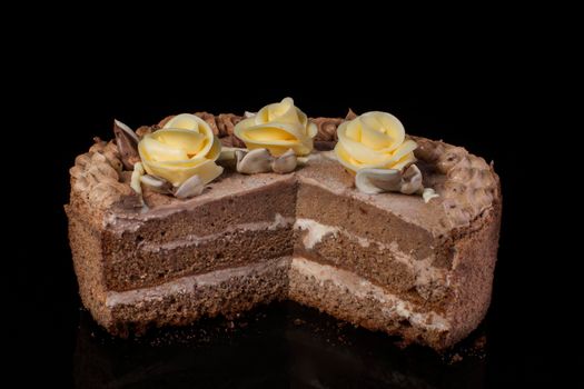 Chunk of chocolate cake decorated with oil cream on a black background