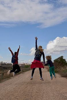 Young blonde woman with two children jumping. Caucasian, sportswear, blue sky , lifestyle, happy