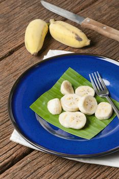 peeled and sliced cultivated banana on blue plate, healthy eating concept