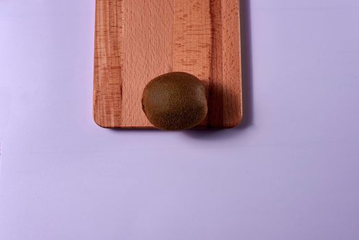 Kiwi on wooden board. Blue background, unique, free space, zenithal view