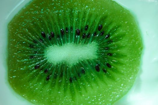 Section of cut ripe kiwifruit. Macro photograph, detail, green, seeds, white