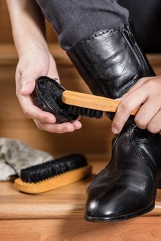 young woman cleaning her black leather boots