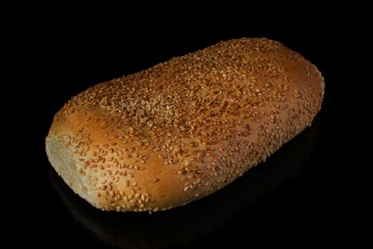 Bread bread sliced with sesame seeds on a black background.loaf