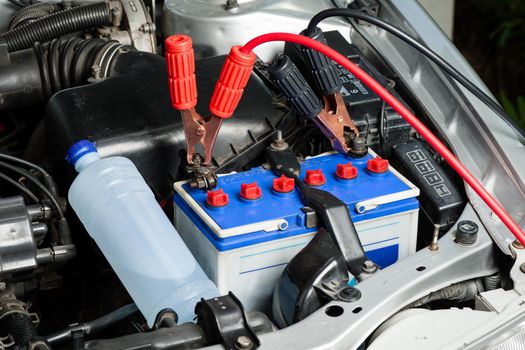 car battery with jumper cable in engine room, car repairing concept