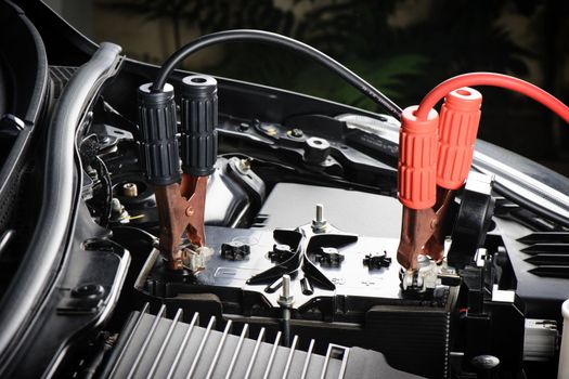 car battery with jumper cable in engine room, car repairing concept