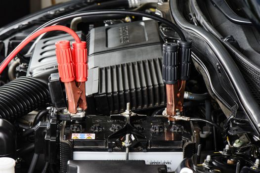 car battery with jumper cable in engine room, car repairing concept