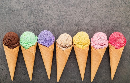 Flat lay various of ice cream cones set up on dark stone background.  Summer and Sweet menu concept.