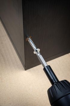 worker screws in a wooden furniture with a screwdriver