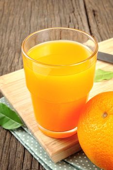 Ripe orange and cup of orange juice on wooden table