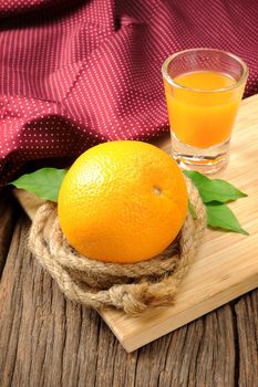 Ripe orange and cup of orange juice on wooden table