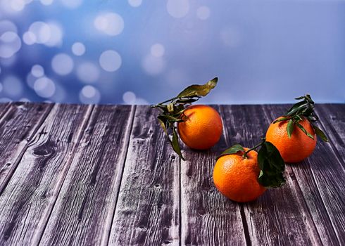 Various oranges with leaves on wooden floor on bright background