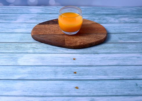 Glass of orange juice on wooden table, on wooden floor with nails and empty space