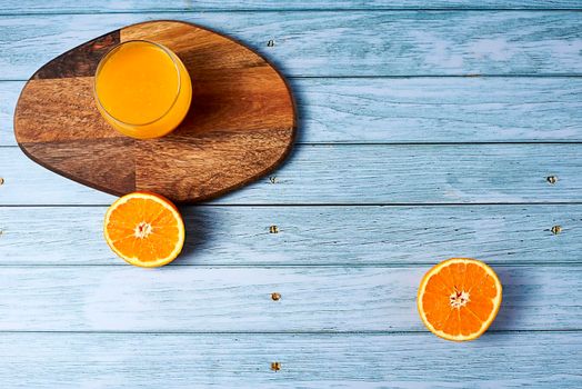 Glass of orange juice on wooden table on wooden floor with nails, free space, overhead view