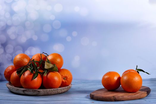 Orange on wooden board and group of oranges on wooden plate on bright background and wooden floor