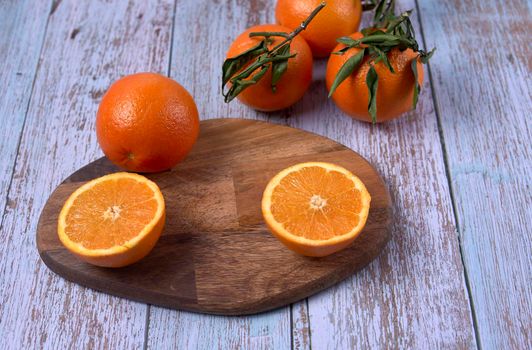 Whole and halved oranges on wooden board on wooden floor