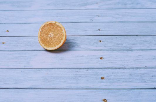 Half orange on light wooden floor with nails, overhead view