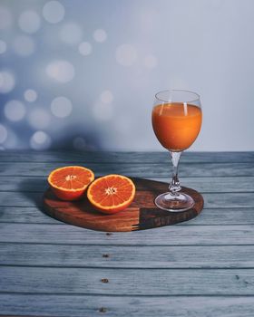 Glass of orange juice on wooden table, half orange, wooden floor, bright sound