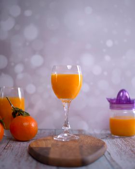 Glass of orange juice. glass juicer, orange juice, wooden table whole oranges with green leaves bright background