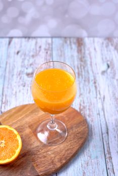 Glass of orange juice on wooden table half orange, wooden floor