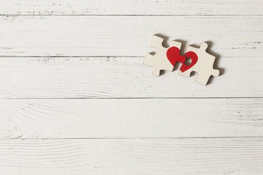 Red heart is drawn on the pieces of the puzzle lying next to each other on white background. Love concept. St. Valentine day
