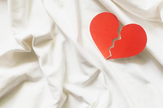 divorce concept - broken red heart on white textile