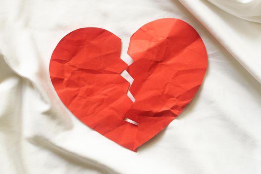 divorce concept - broken red paper heart on white textile