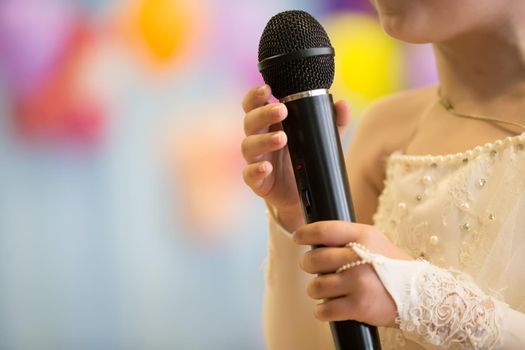 Children's hands hold a microphone