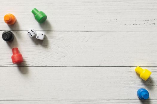 Multi-colored game chips with dices on wooden board. Board game.
